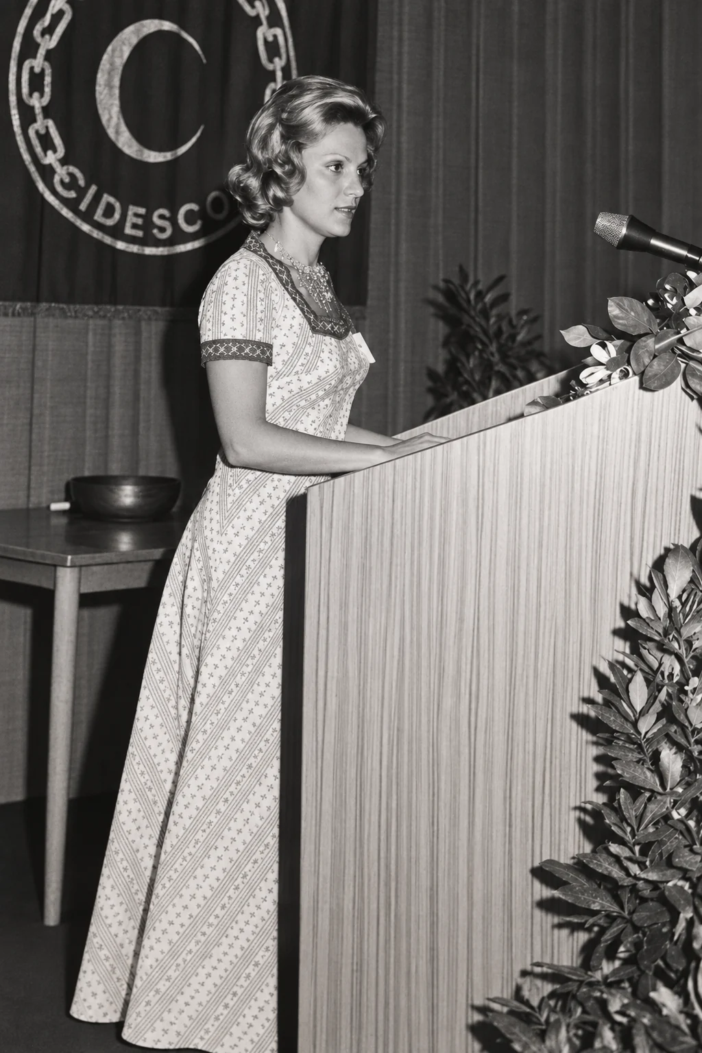 Archival black and white photograph of the founders’ mother speaking at a podium